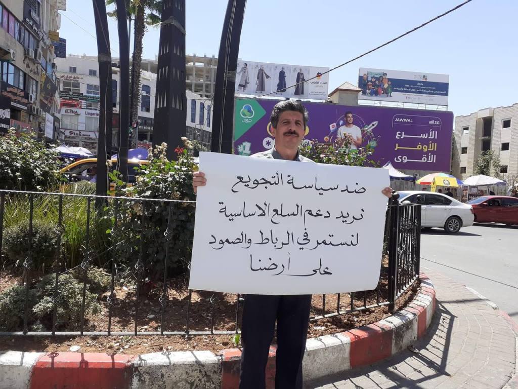 In the middle of Hebron
A Palestinian raises a banner
against high prices and high living prices. #الخليل.