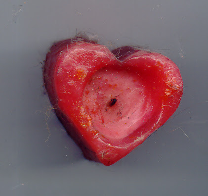 a candle in the shape of a heart covered with dust