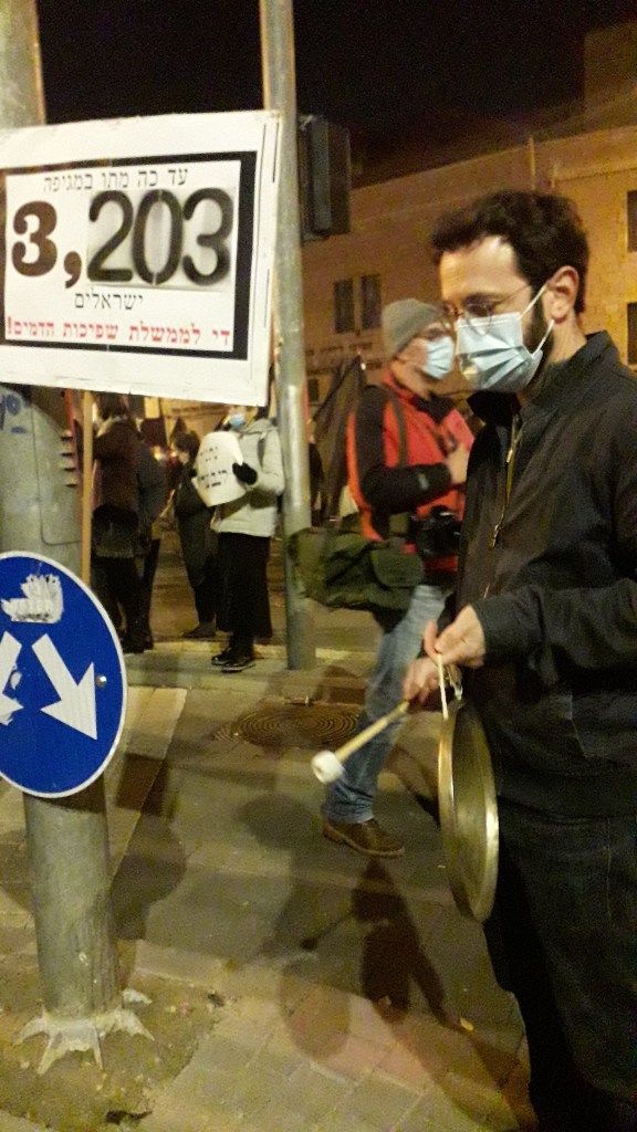 מפגין בבלפור נגד ממשלת נתניהו מחזיק שלט עם מספר הנפטרים מן המגיפה